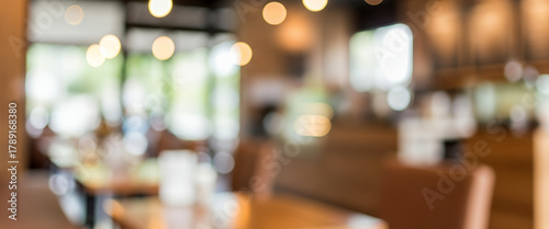 Blurred cafe interior with warm lighting, wooden textures, and soft focus. Modern seating area and decorative elements, suitable for lifestyle and creative backgrounds.