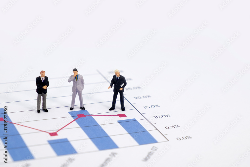 Fototapeta premium Miniature figures businessman standing on a graph chart financial with copy space using as background. businessman analyze achievement data