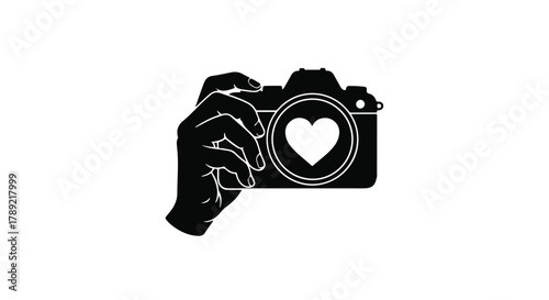 Hand holding camera with heart symbol, symbolizing passion for photography and capturing love.