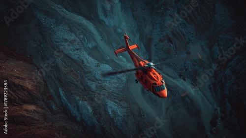Red rescue helicopter flying over dramatic mountain canyon landscape at dusk, aerial emergency aircraft in dark blue and orange light contrast
