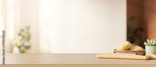 Fototapeta Naklejka Na Ścianę i Meble -  Bread on plate and knife on cutting board with pot plant on wooden cooking counter in bright kitchen