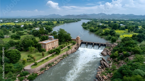 Aerial view of a river dam with strong water flow an adjacent power plant building and green rural landscape