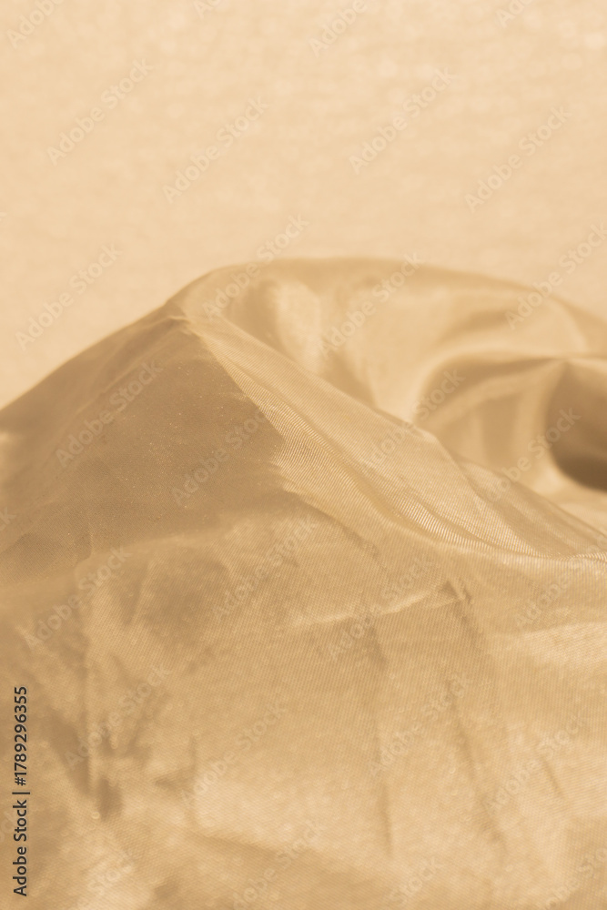 Obraz premium Golden color background, close-up photograph showcasing the delicate texture and movement of highly sheer, lightweight fabric.