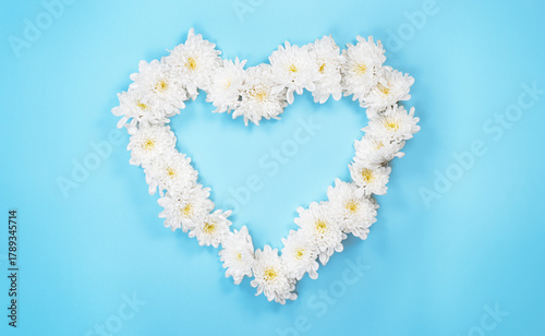 White Flowers Heart on Blue Paper Surface. Top View Photo. Wallpaper Background Template.