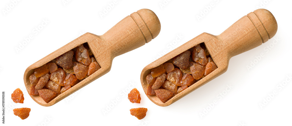 Obraz premium Crushed amber in the wooden scoop, isolated on white background, top view.