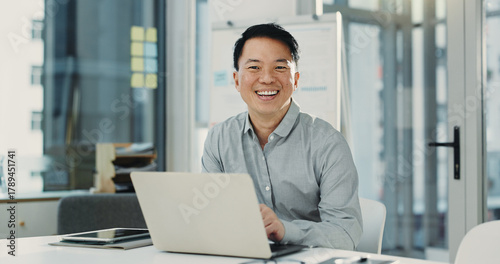 Portrait, laptop and Asian man in office for business, compliance consultant and laugh. Computer, happy advisor and mature person with pride for policy development, confidence or funny in South Korea