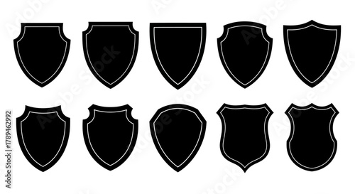 Collection of ten different black shield silhouettes with textured edges on a white background
