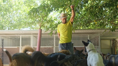 Dog trainer raising his fist surrounded by a pack of canines