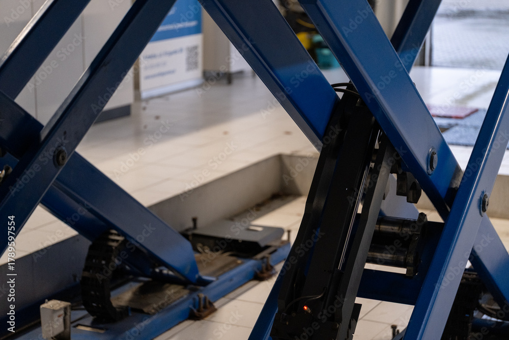 Naklejka premium Hydraulic car lift platform in modern auto service workshop