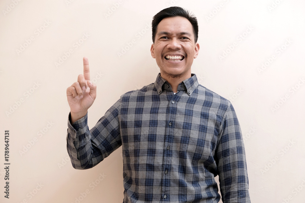 Fototapeta premium Southeast Asian man wearing flannel shirt showing happy excited expression with giving number 12345 by hand gesture, on white isolated background.