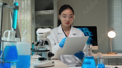 Asian female scientist writing research data in laboratory