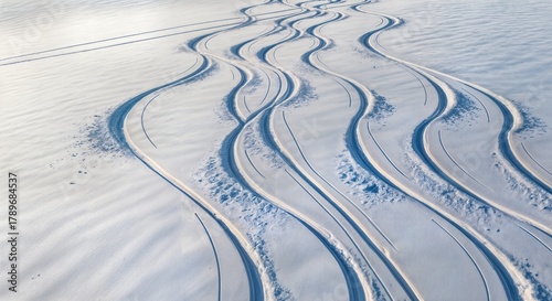  Aerial winter mountain slope with fresh ski and snowboard tracks creating graphic S curves in pristine snow 