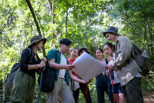 Group of friends studying map while trekking forest