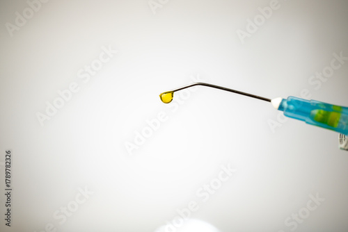 Foto Gloved hand holding a pre-filled syringe with yellow Riboflavin solution and a hypodermic needle