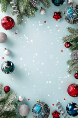 Vertical bright light blue Christmas background with a decorative border of snowy fir branches, swirling ribbons, and vibrant red, silver, and patterned teal baubles