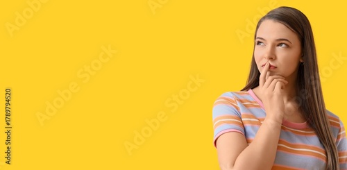 Thoughtful young woman on yellow background with space for text