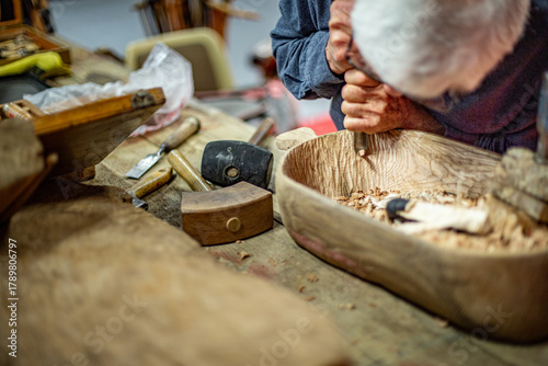 Artisan hands carving wood bowl with chisel