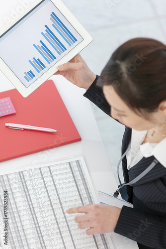 タブレット端末を持ってデスクワークをするビジネスウーマン 