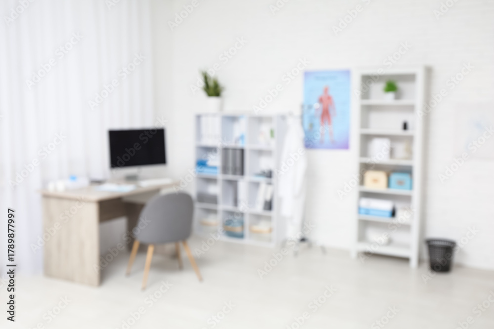 Fototapeta premium Blurred view of medical office with doctor's workplace and shelf units