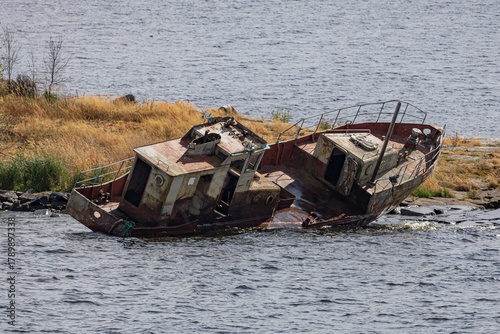 An old abandoned riverboat lies by the shore