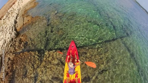 Couple paddling a kayak over crystal-clear turquoise water along a rocky Croatian coast, aerial top view capturing summer adventure, active travel and seaside recreation in Cape Kamenjak Natural Park