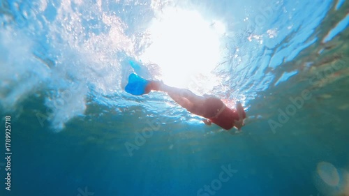 man wearing fins and mask swimming underwater in clear blue sea of Blue Lagoon, enjoying summer vacation exploring vibrant aquatic environment with sun rays in Drvenik Veli island of Croatia