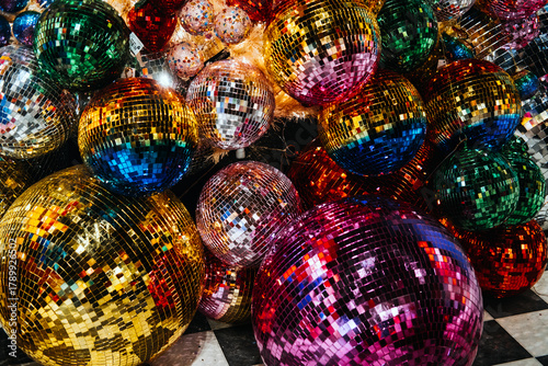 Photos Cluster of large multicolored disco balls reflecting light in a festive indoor setup with a checkered floor
