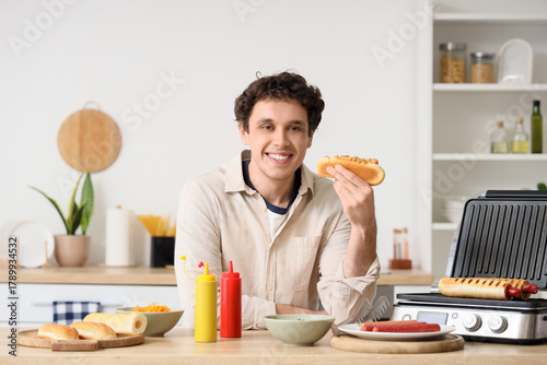 Young man cooking hot dogs ...
