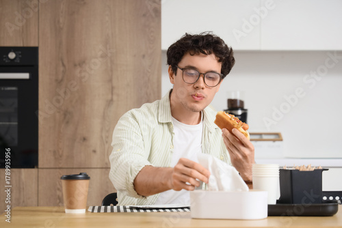 Young man with tissue eatin...