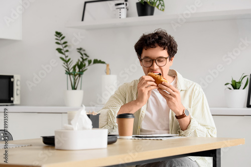 Young man eating tasty hot ...