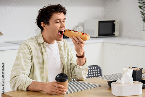 Young man with coffee eatin...