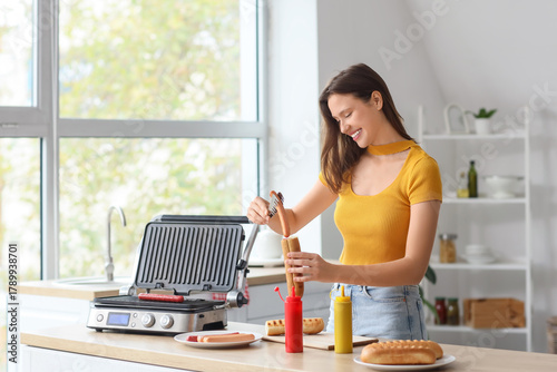 Young woman cooking hot dog...