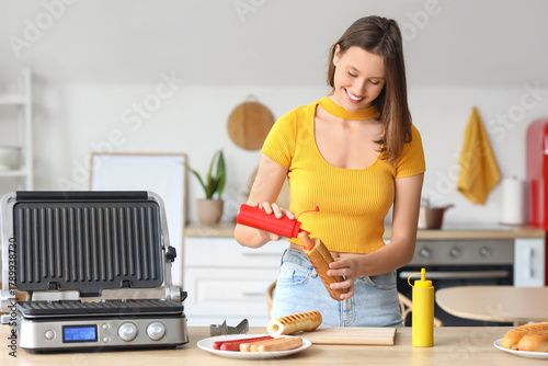 Young woman cooking hot dog...