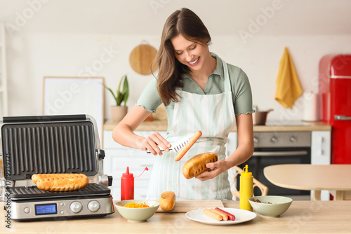 Young woman cooking hot dog...