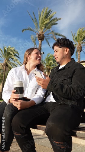 Young generation z couple laughing together outdoors on a bench