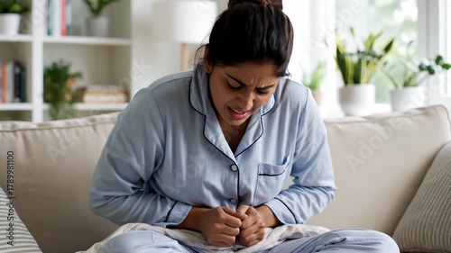 Woman Holding Stomach in Pain on Couch