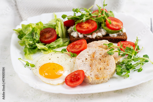 English breakfast. Fried egg, chicken meatloaf and sandwich with tomatoes, avocado and cheese.
