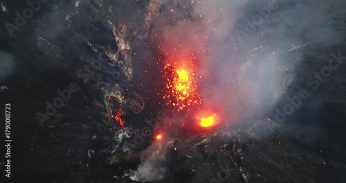 Yasur volcano actively erupting in a dramatic aerial drone view, showcasing hot molten lava exploding from the crater and flowing down the rugged volcanic landscape on Tanna Island in Vanuatu