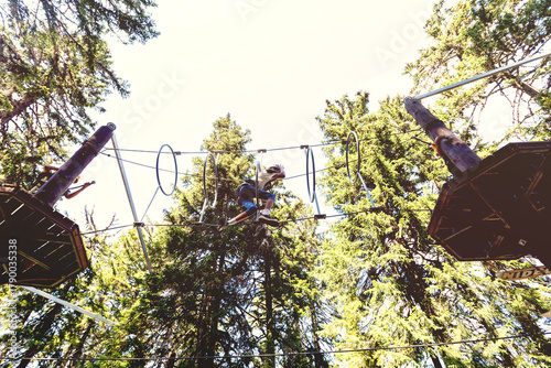 Adventure park challenge in forest setting with safety gear and suspended rope