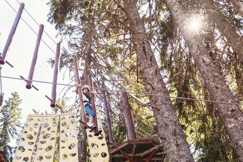 Adventure park challenge in forest setting with safety gear and suspended rope