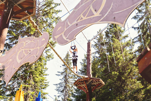 Adventure park challenge in forest setting with safety gear and suspended rope