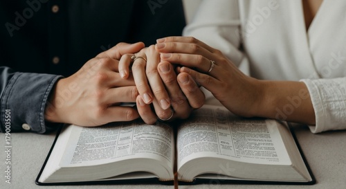 A couple's hands clasped together over an open Bible, symbolizing faith and love.