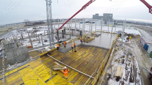 Aerial view of office development in Poland, workers pouring reinforced concrete slab. Real estate growth, urban infrastructure, EU investment.