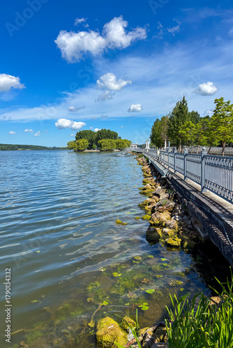 A peaceful walk unfolds along the Ternopil Pond in Ternopil, Ukraine, where calm waters and lush surroundings create a serene urban retreat.
