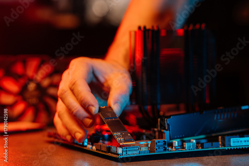 person installs an M.2 NVMe SSD into a modern motherboard connector, demonstrating the assembly of computer equipment in the process.