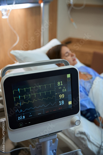 Female patient in hospital with heart rate monitor in foreground