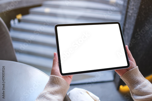 Mockup image of a woman holding digital tablet with blank white desktop screen in cafe