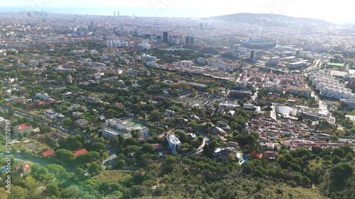 Barcelona cityscape showcasing the diverse urban landscape from an elevated perspective, featuring residential neighborhoods, sports facilities, and the sea under a clear sky