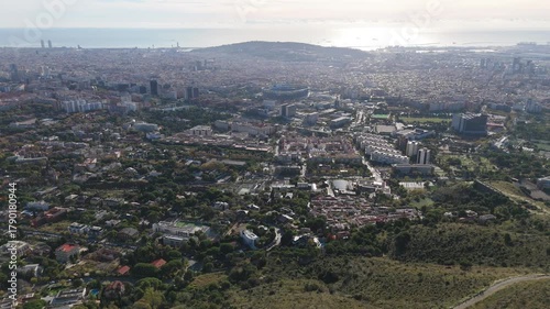 Barcelona cityscape showcasing the diverse urban landscape from an elevated perspective, featuring residential neighborhoods, sports facilities, and the sea under a clear sky
