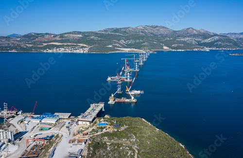 Aerial view of the Peljesac Bridge construction site over the shimmering blue waters, a testament to human engineering, Brijesta, Dubrovnik-Neretva County, Croatia.